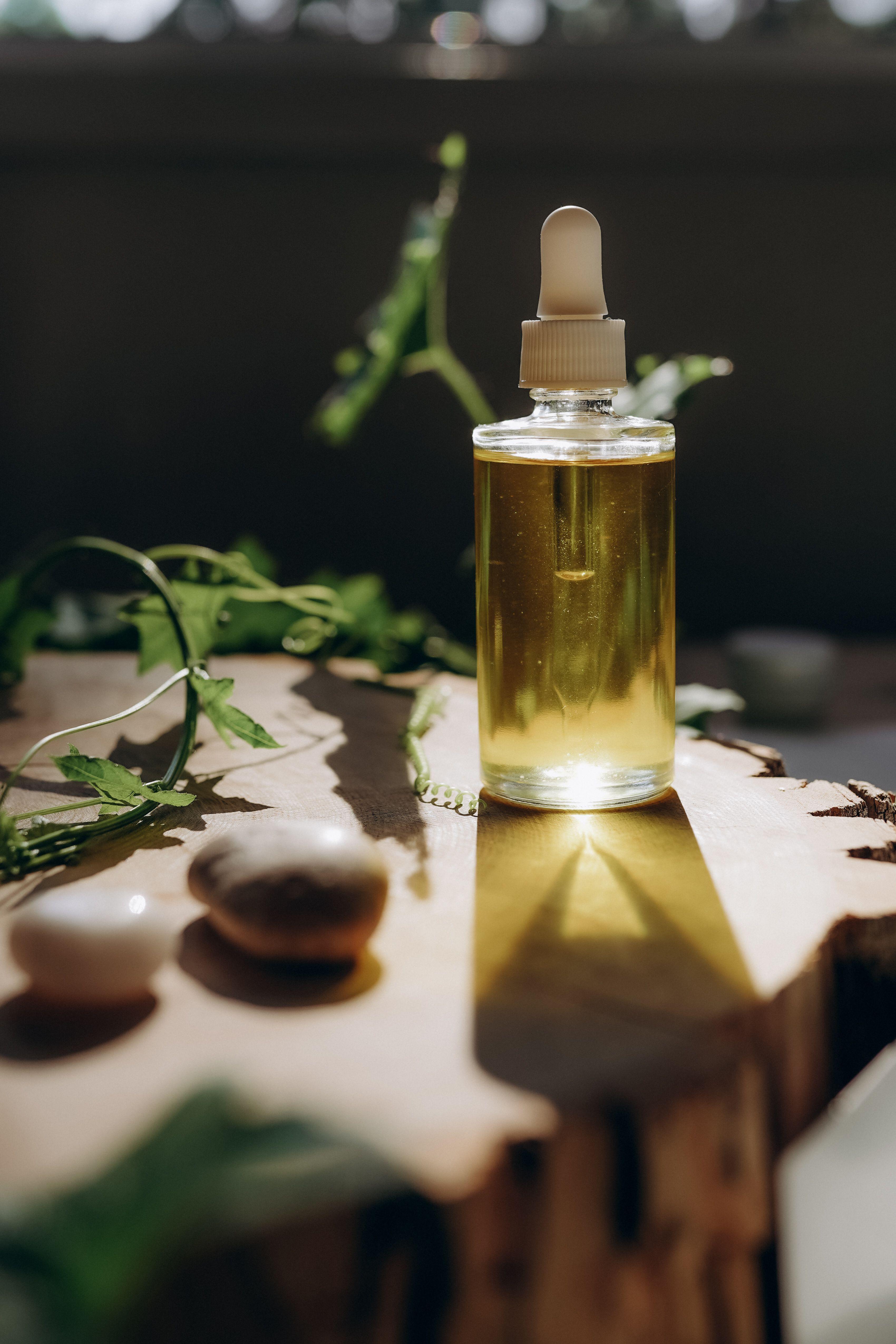 A bottle of golden cooking oil resting on a wooden surface in warm natural light.