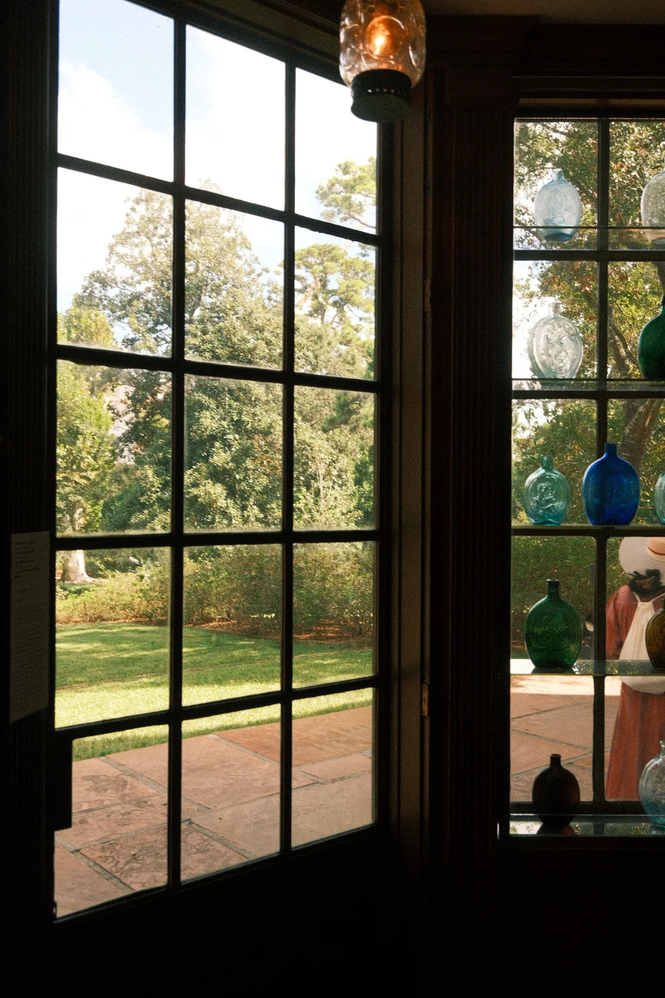 Garden light through a glass doorway, with colored glass objects beside the window.